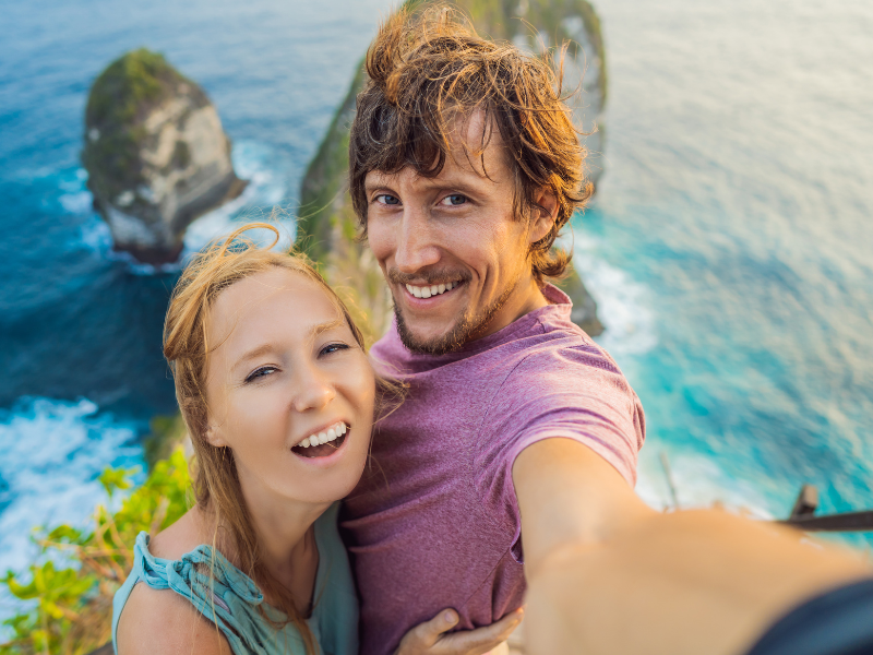 Smiling tourist taking a selfie with a stunning Bali beach