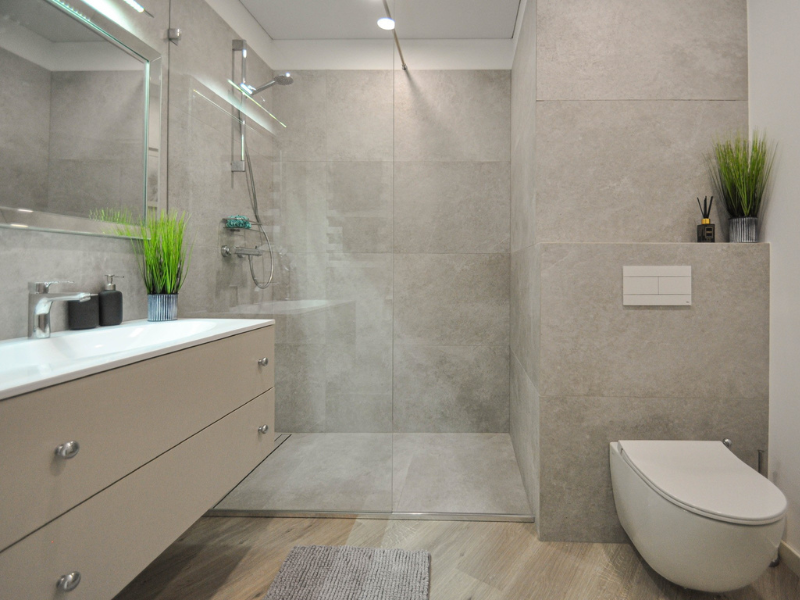 Modern bathroom in a Lithuania recovery apartment with a transparent shower door and a white commode, designed for patient comfort.