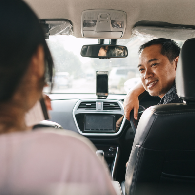 Asian taxi driver looking behind and smiling to the passenger